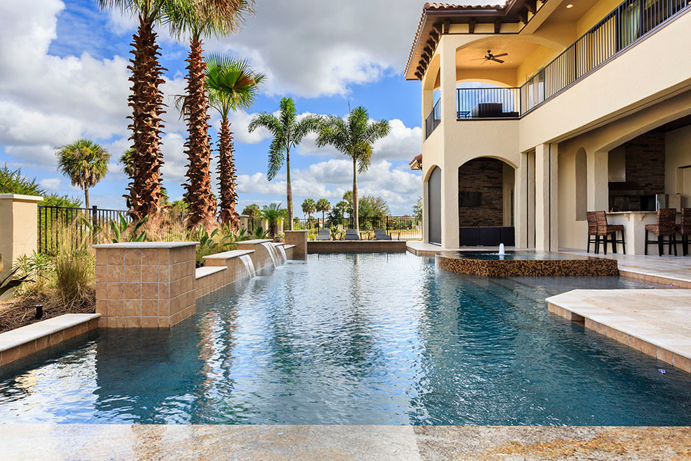Inspiration for a large backyard rectangular infinity pool in Orlando with a water feature and brick pavers.