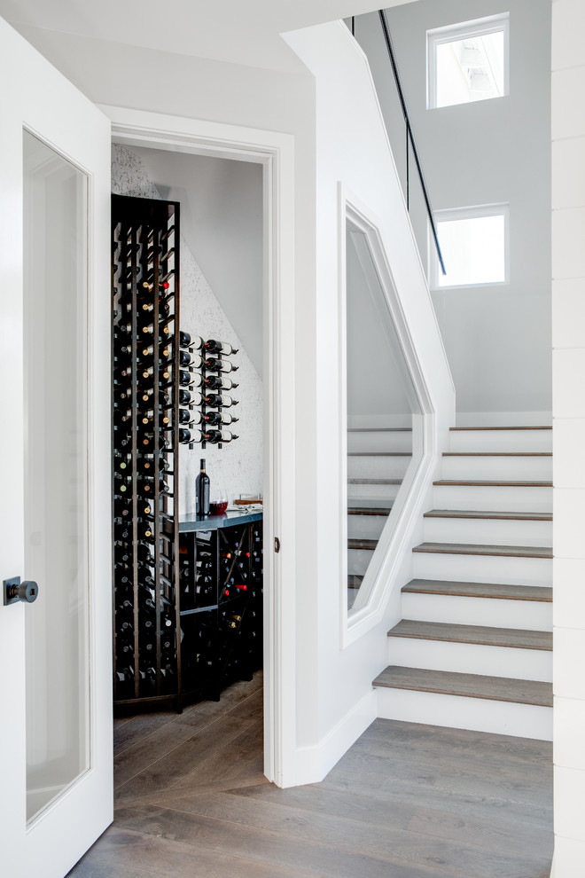 Design ideas for a mid-sized wine cellar in Los Angeles with medium hardwood floors, storage racks and brown floor.