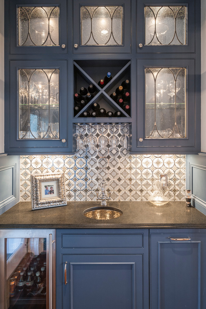 Photo of a small traditional galley wet bar in Cincinnati with beaded inset cabinets, blue cabinets, granite benchtops, blue splashback, mosaic tile splashback and an undermount sink.