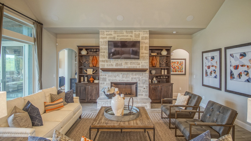 Large transitional open concept living room in Austin with grey walls, porcelain floors, a standard fireplace, a stone fireplace surround, a wall-mounted tv and grey floor.