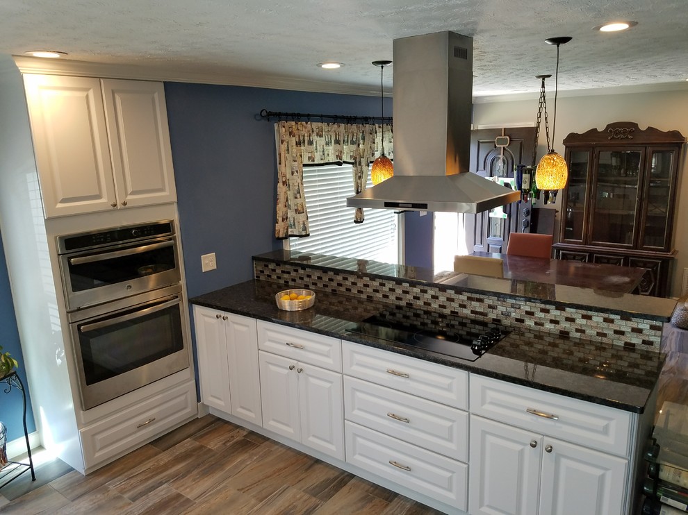 Example of a mid-sized transitional galley medium tone wood floor and beige floor eat-in kitchen design in Atlanta with an undermount sink, raised-panel cabinets, white cabinets, quartz countertops, beige backsplash, subway tile backsplash, stainless steel appliances and a peninsula