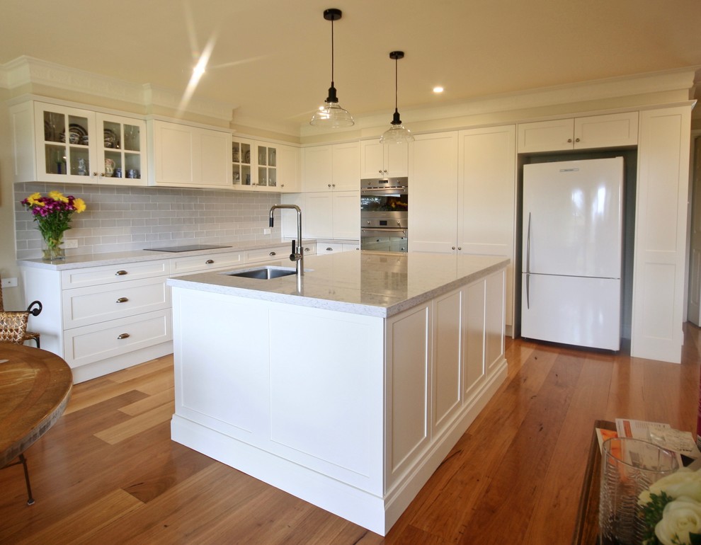 Design ideas for a large transitional l-shaped open plan kitchen in Sydney with an undermount sink, shaker cabinets, white cabinets, quartz benchtops, grey splashback, ceramic splashback, stainless steel appliances, medium hardwood floors and with island.