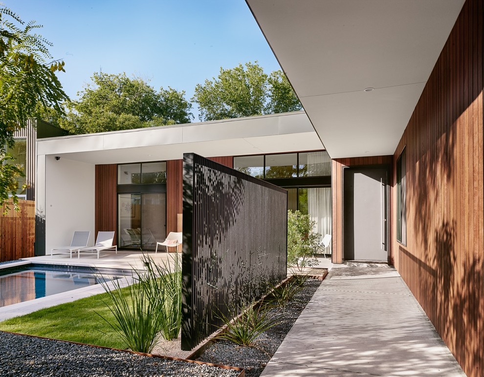 This is an example of a mid-sized contemporary partial sun courtyard gravel retaining wall landscape in Austin.