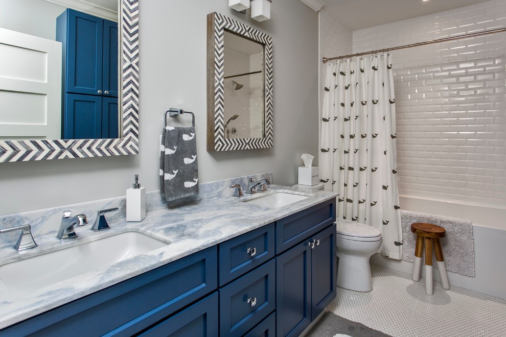 This is an example of a large contemporary kids bathroom in Portland Maine with shaker cabinets, blue cabinets, white tile, subway tile, ceramic floors, marble benchtops, an alcove tub, a shower/bathtub combo, a two-piece toilet, grey walls, an undermount sink and blue benchtops.