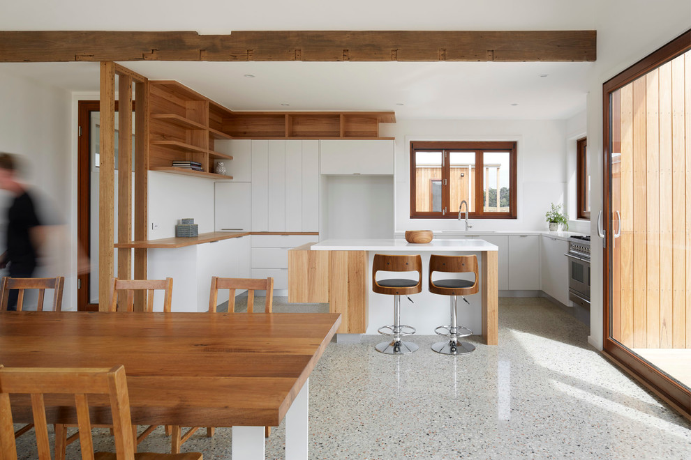 Mid-sized scandinavian u-shaped eat-in kitchen in Melbourne with a double-bowl sink, flat-panel cabinets, white cabinets, quartz benchtops, white splashback, glass sheet splashback, stainless steel appliances, concrete floors and with island.