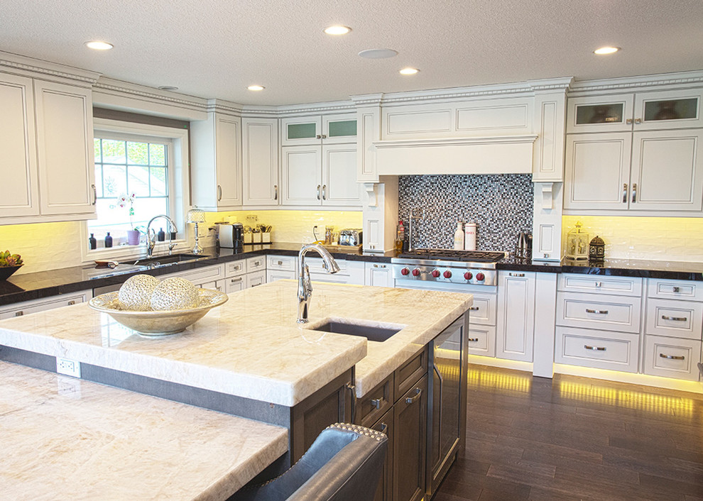 Example of a mid-sized transitional u-shaped dark wood floor and brown floor eat-in kitchen design with an undermount sink, shaker cabinets, white cabinets, granite countertops, multicolored backsplash, stainless steel appliances and an island