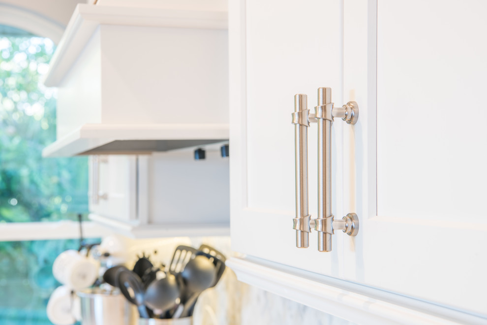 Inspiration for a large transitional u-shaped porcelain tile and brown floor eat-in kitchen remodel with an undermount sink, shaker cabinets, white cabinets, quartz countertops, white backsplash, marble backsplash, stainless steel appliances and two islands