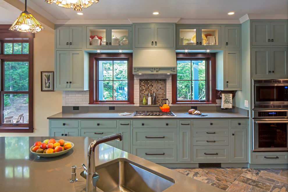 Large arts and crafts single-wall eat-in kitchen in Portland Maine with an undermount sink, shaker cabinets, green cabinets, quartz benchtops, white splashback, subway tile splashback, with island, multi-coloured floor and grey benchtop.