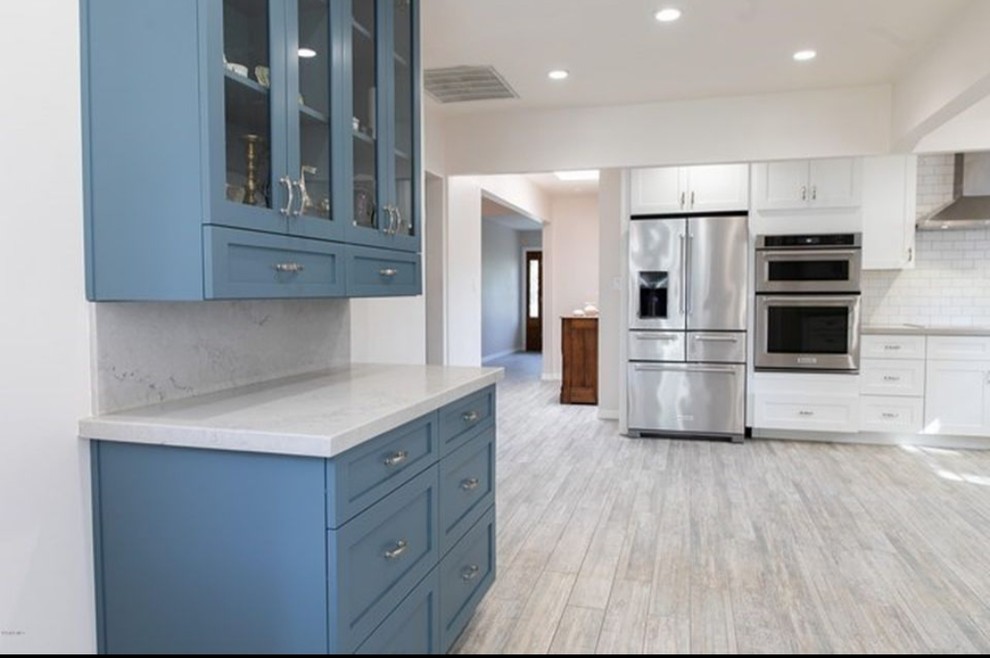 Design ideas for a large contemporary u-shaped separate kitchen in Orange County with a farmhouse sink, shaker cabinets, white cabinets, limestone benchtops, white splashback, subway tile splashback, stainless steel appliances, porcelain floors, no island, beige floor and grey benchtop.