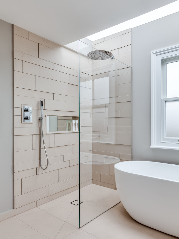 Photo of a contemporary bathroom in London with a freestanding tub, beige tile, grey walls, a curbless shower and a niche.