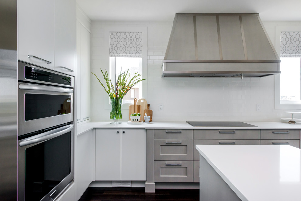 Example of a large transitional l-shaped dark wood floor eat-in kitchen design in Calgary with a farmhouse sink, flat-panel cabinets, quartz countertops, white backsplash, subway tile backsplash, stainless steel appliances and an island