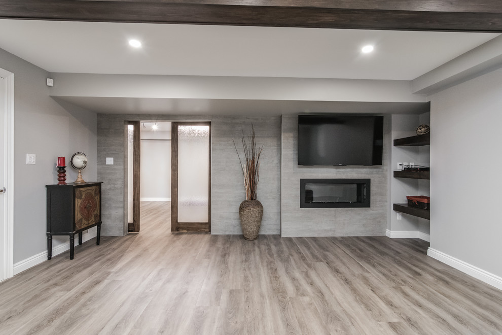 Inspiration for a large transitional look-out basement in Toronto with grey walls, vinyl floors, a hanging fireplace, a concrete fireplace surround and brown floor.