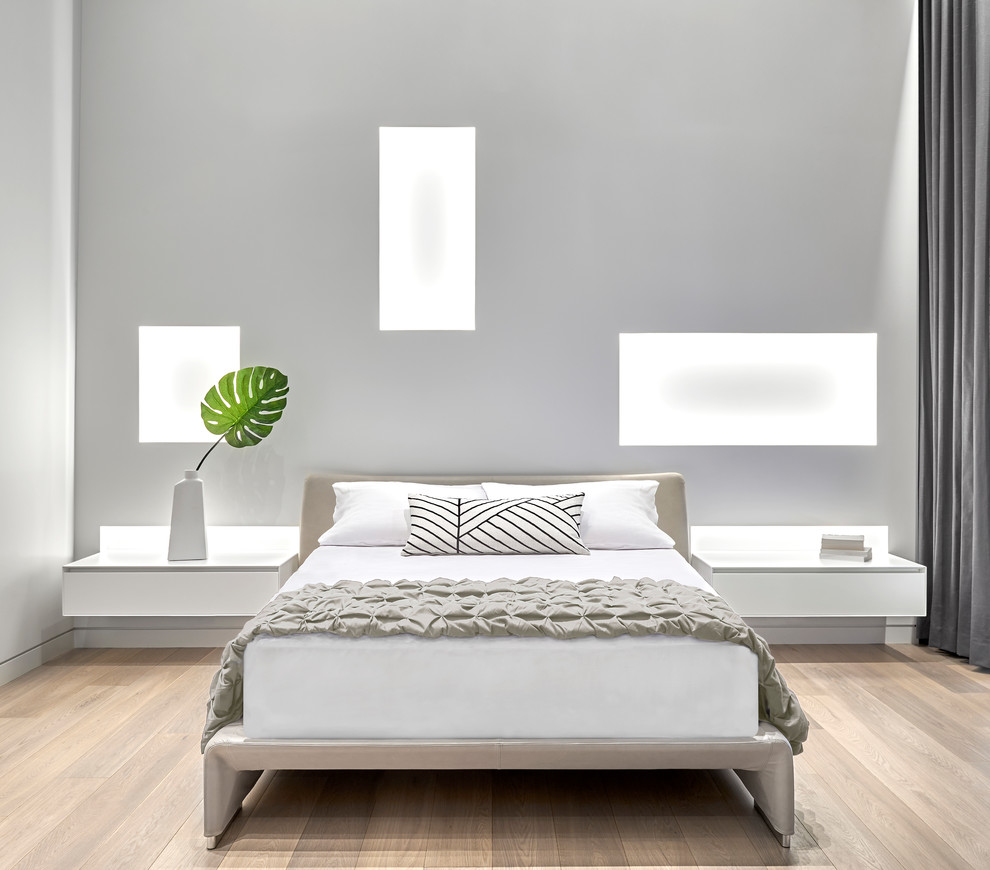 This is an example of a large contemporary master bedroom in Chicago with white walls and light hardwood floors.