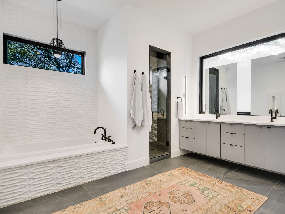 Inspiration for a mid-sized contemporary master bathroom in Austin with flat-panel cabinets, grey cabinets, a drop-in tub, white tile, ceramic tile, white walls, porcelain floors, an undermount sink, engineered quartz benchtops, grey floor, a hinged shower door, white benchtops, an alcove shower and a double vanity.