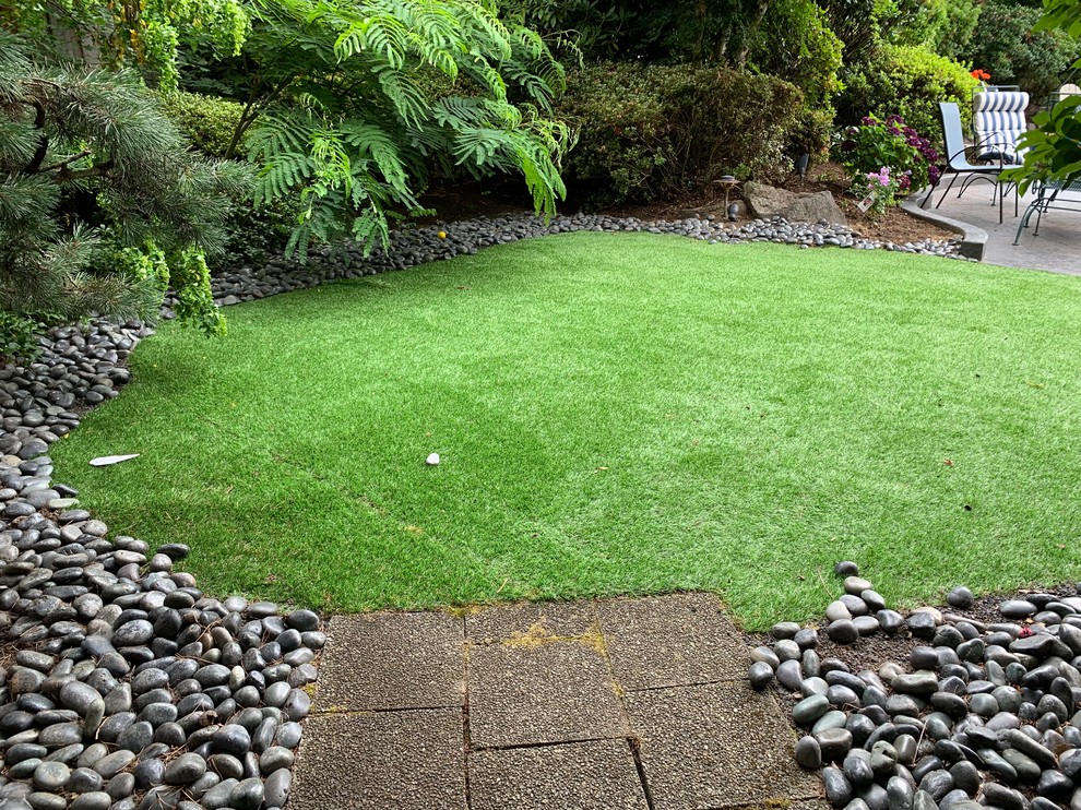 Design ideas for a mid-sized transitional backyard full sun xeriscape in Portland with river rock.