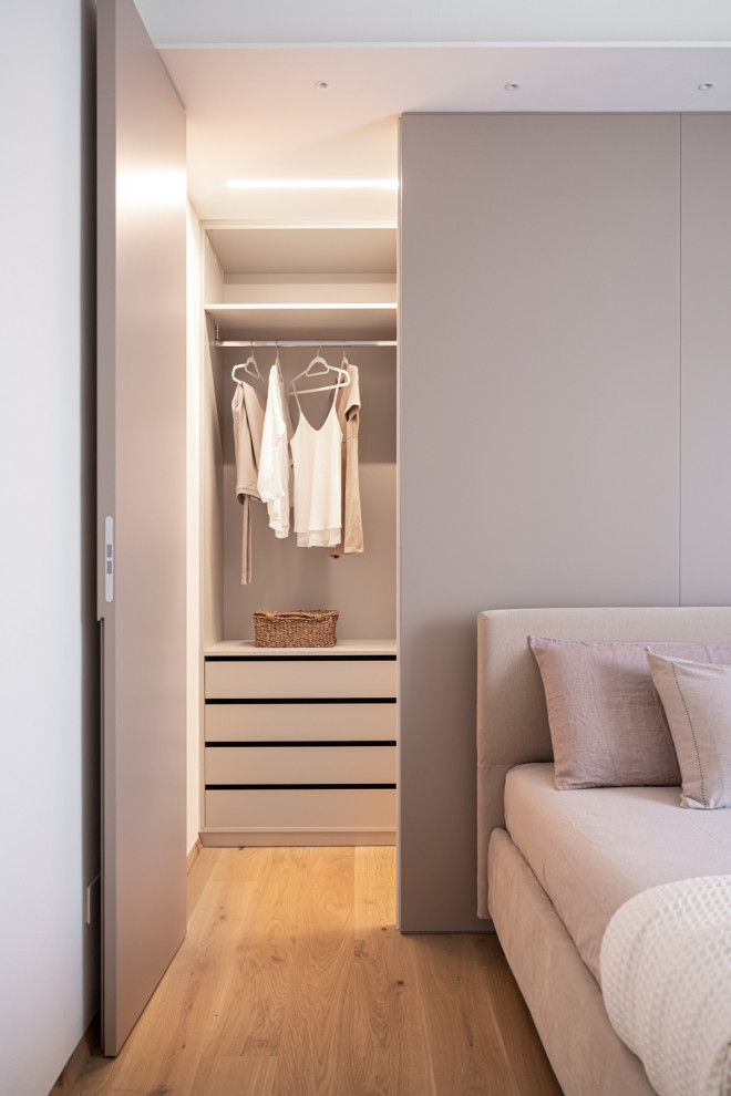 Diseño de dormitorio principal moderno con paredes blancas, suelo de madera clara, suelo marrón y bandeja