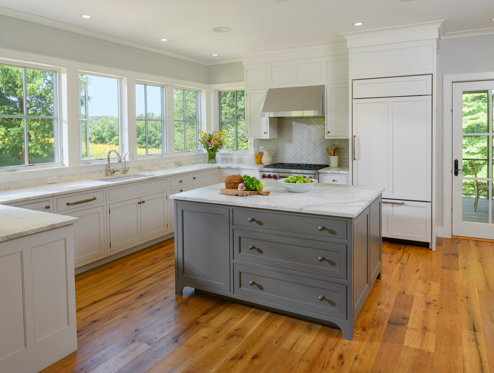 Photo of a mid-sized traditional l-shaped kitchen in Philadelphia with an undermount sink, beaded inset cabinets, white cabinets, marble benchtops, grey splashback, subway tile splashback, stainless steel appliances, light hardwood floors and with island.