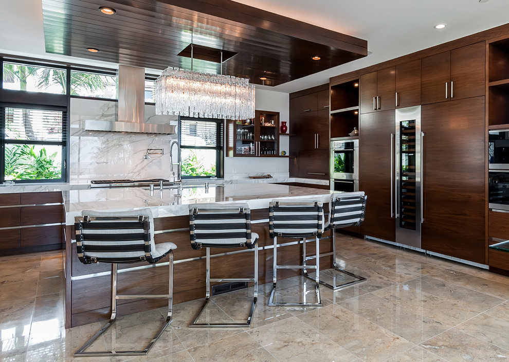 Expansive contemporary l-shaped kitchen in Los Angeles with an undermount sink, flat-panel cabinets, dark wood cabinets, marble benchtops, white splashback, marble splashback, marble floors, with island, beige floor and panelled appliances.