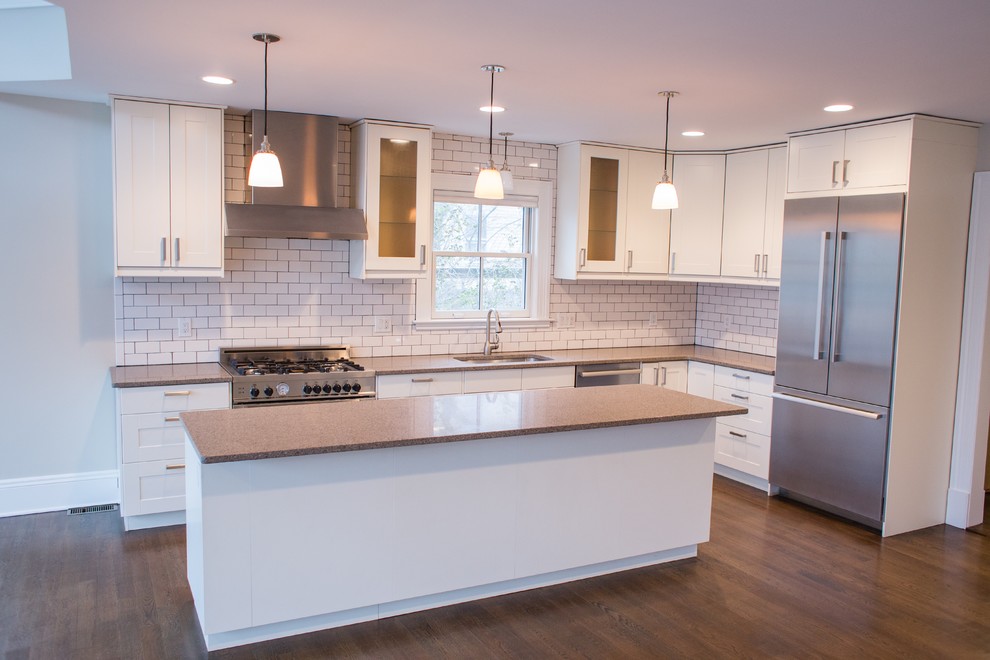 Mid-sized transitional l-shaped dark wood floor open concept kitchen photo in New York with an undermount sink, shaker cabinets, white cabinets, granite countertops, white backsplash, subway tile backsplash, stainless steel appliances and an island