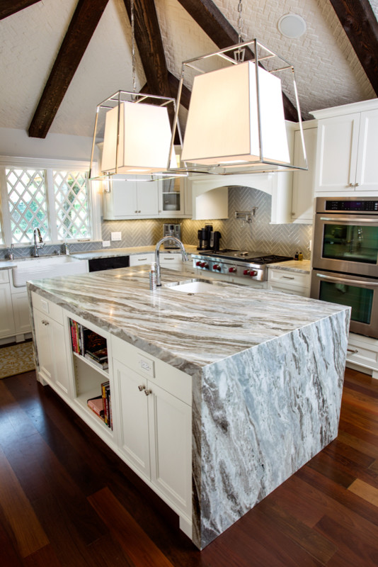 Kitchen - large transitional l-shaped dark wood floor kitchen idea with a farmhouse sink, shaker cabinets, white cabinets, quartzite countertops, gray backsplash, glass tile backsplash, stainless steel appliances and an island
