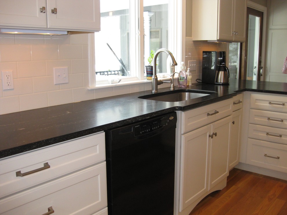 Eat-in kitchen - transitional l-shaped medium tone wood floor eat-in kitchen idea in Boston with an undermount sink, shaker cabinets, white cabinets, quartz countertops, white backsplash, ceramic backsplash, stainless steel appliances, an island and black countertops
