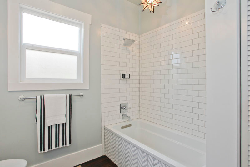 Photo of a mid-sized contemporary master bathroom in San Francisco with furniture-like cabinets, grey cabinets, marble benchtops, a corner tub, a shower/bathtub combo, a two-piece toilet, white tile, grey walls and dark hardwood floors.