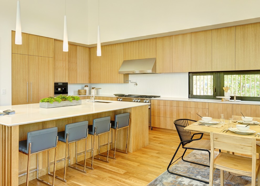 Photo of an expansive asian l-shaped eat-in kitchen in Other with an undermount sink, flat-panel cabinets, light wood cabinets, quartzite benchtops, white splashback, glass tile splashback, stainless steel appliances, light hardwood floors, with island and beige floor.
