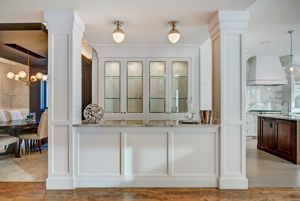 Example of a transitional galley kitchen design in Calgary with shaker cabinets, white cabinets, marble countertops and stainless steel appliances