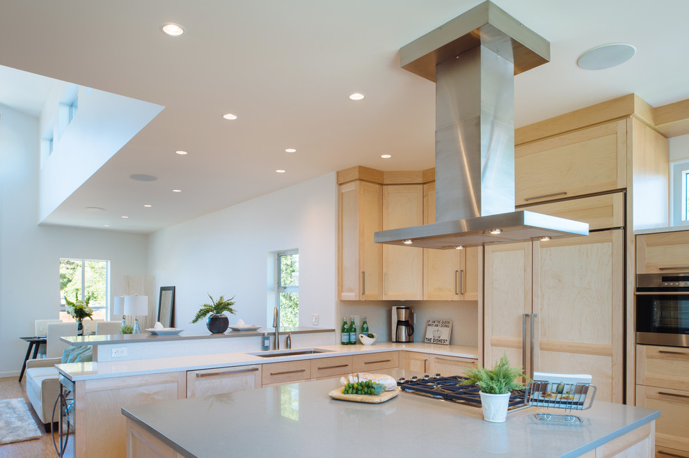This is an example of a contemporary u-shaped open plan kitchen in Vancouver with an undermount sink, shaker cabinets, light wood cabinets, quartz benchtops, stone tile splashback, panelled appliances, cork floors and with island.