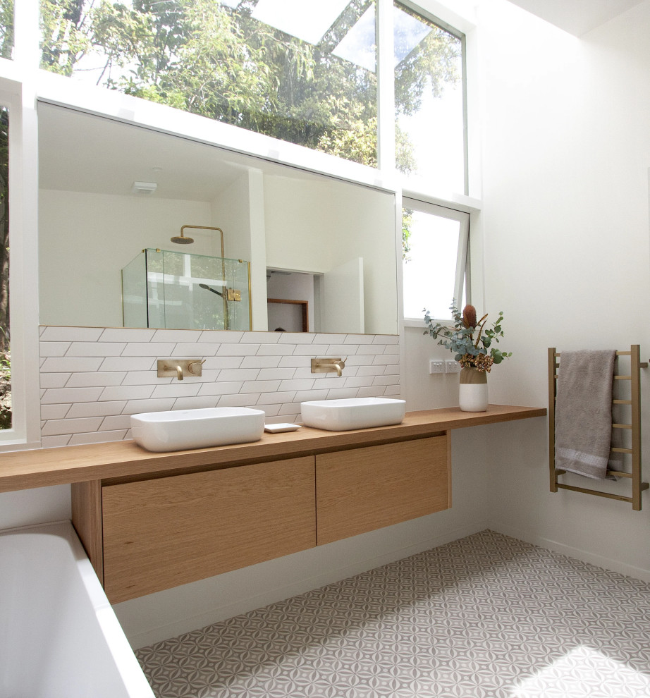 Mid-sized scandinavian kids bathroom in Perth with furniture-like cabinets, medium wood cabinets, a freestanding tub, a corner shower, white tile, ceramic tile, white walls, porcelain floors, a vessel sink, wood benchtops, multi-coloured floor, a hinged shower door, a double vanity, a floating vanity and timber.