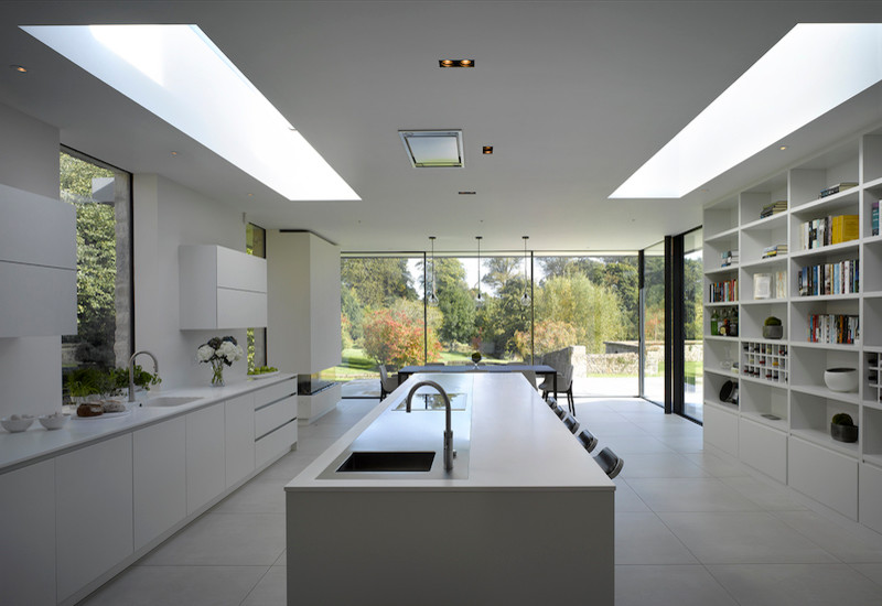 Design ideas for a large modern l-shaped eat-in kitchen in London with flat-panel cabinets, white cabinets, solid surface benchtops, white splashback and with island.