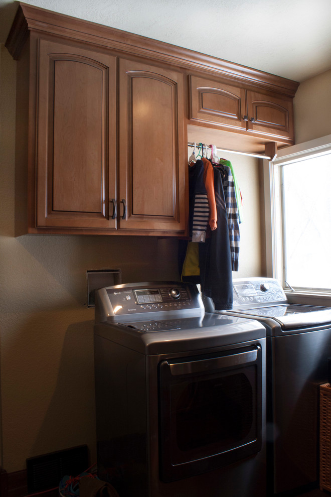 Laundry room - small transitional laundry room idea with raised-panel cabinets, light wood cabinets, beige walls and a side-by-side washer/dryer