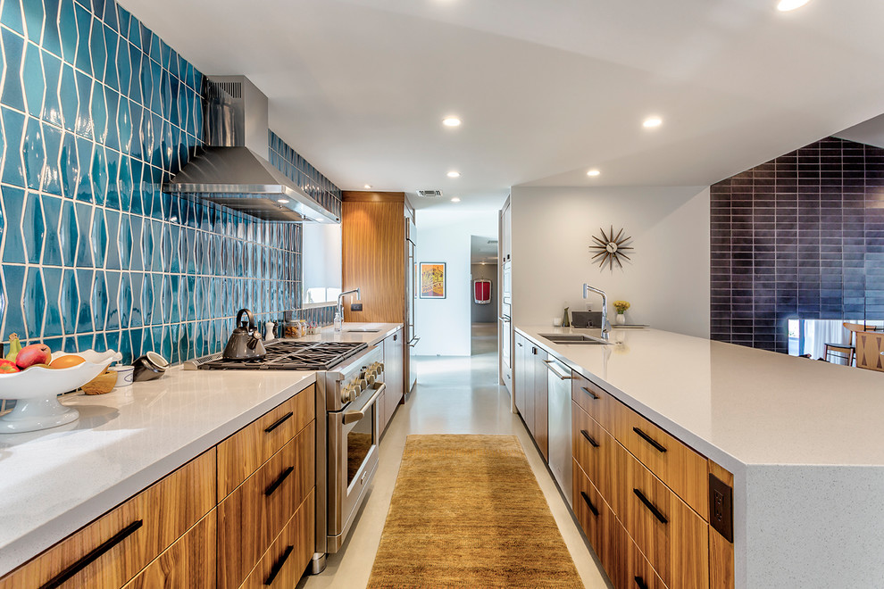 Photo of a midcentury galley eat-in kitchen in Phoenix with an undermount sink, flat-panel cabinets, medium wood cabinets, quartz benchtops, blue splashback, ceramic splashback, stainless steel appliances, concrete floors, a peninsula and grey floor.