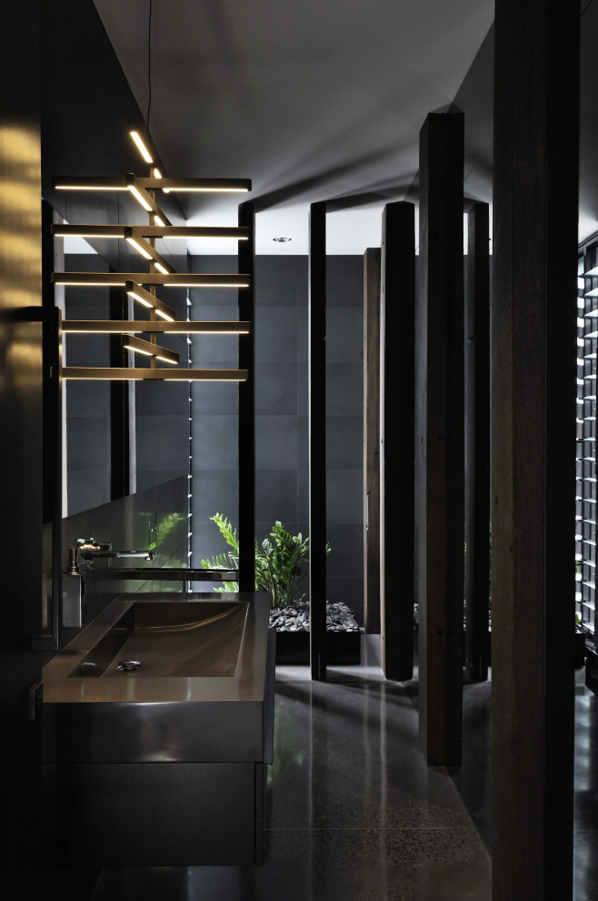 Immagine di una stanza da bagno design con ante nere, lavabo integrato, top in superficie solida, pavimento nero, top nero e un lavabo