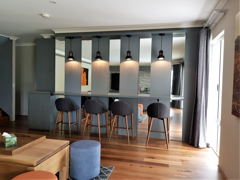 Photo of a large modern single-wall home bar in Perth with medium wood cabinets, laminate benchtops, medium hardwood floors and brown floor.