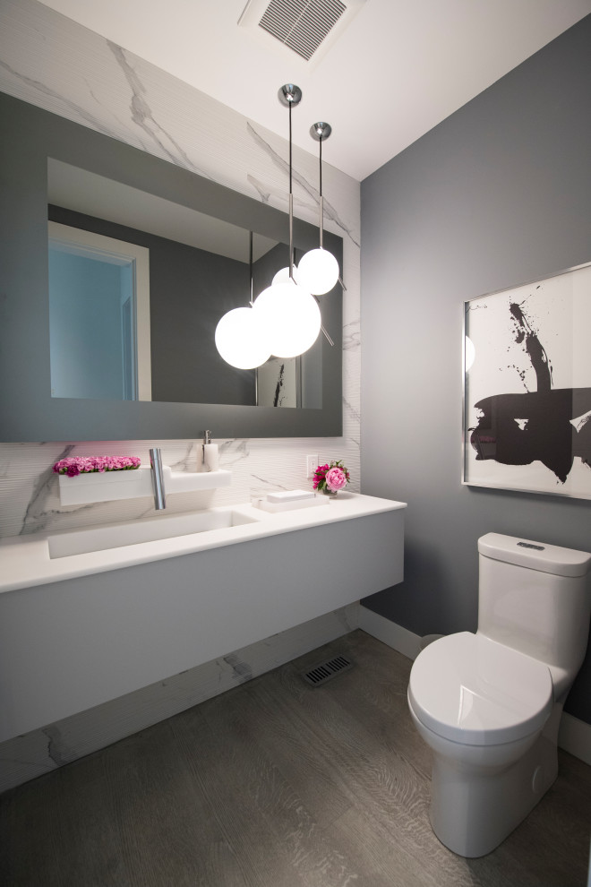 This is an example of a mid-sized contemporary powder room in Toronto with white cabinets, a one-piece toilet, white tile, porcelain tile, grey walls, an integrated sink, beige floor, white benchtops and a floating vanity.