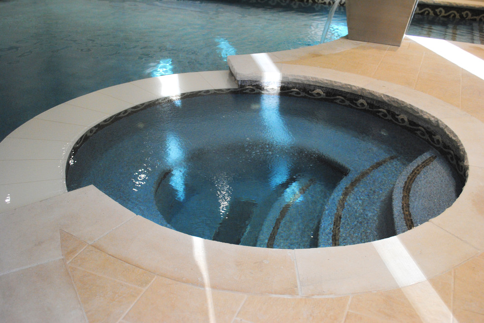 Photo of a large transitional custom-shaped pool in Toronto with a hot tub and natural stone pavers.