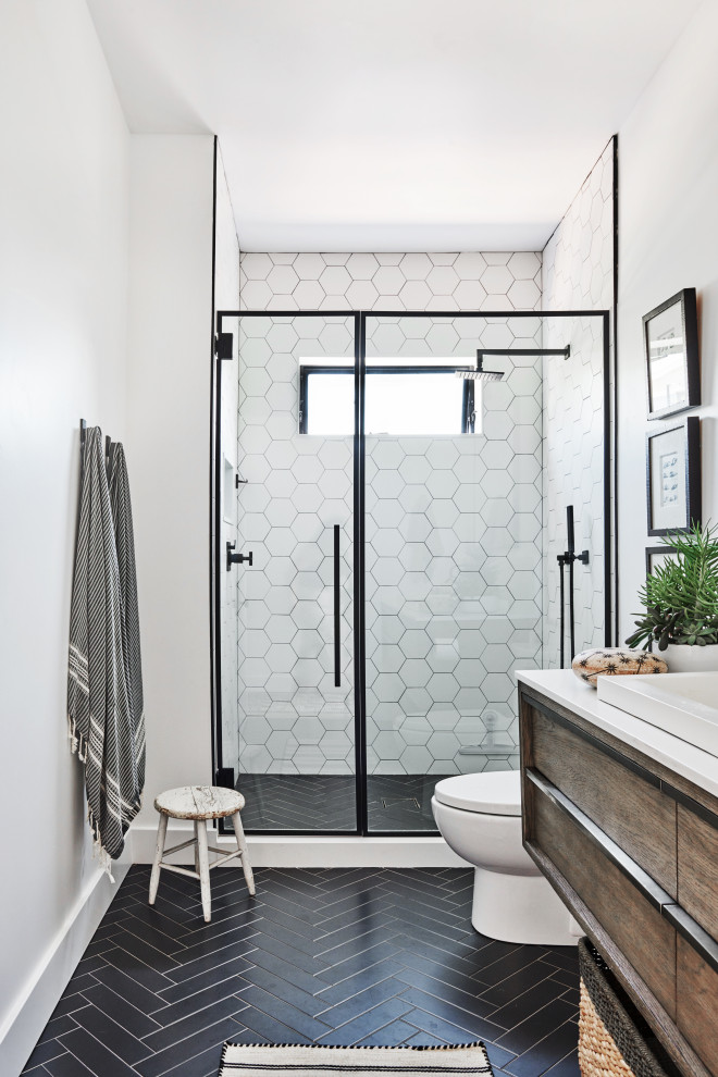 Mid-sized contemporary 3/4 bathroom in Los Angeles with brown cabinets, an alcove shower, a one-piece toilet, white tile, ceramic tile, white walls, ceramic floors, a drop-in sink, engineered quartz benchtops, black floor, a hinged shower door and white benchtops.