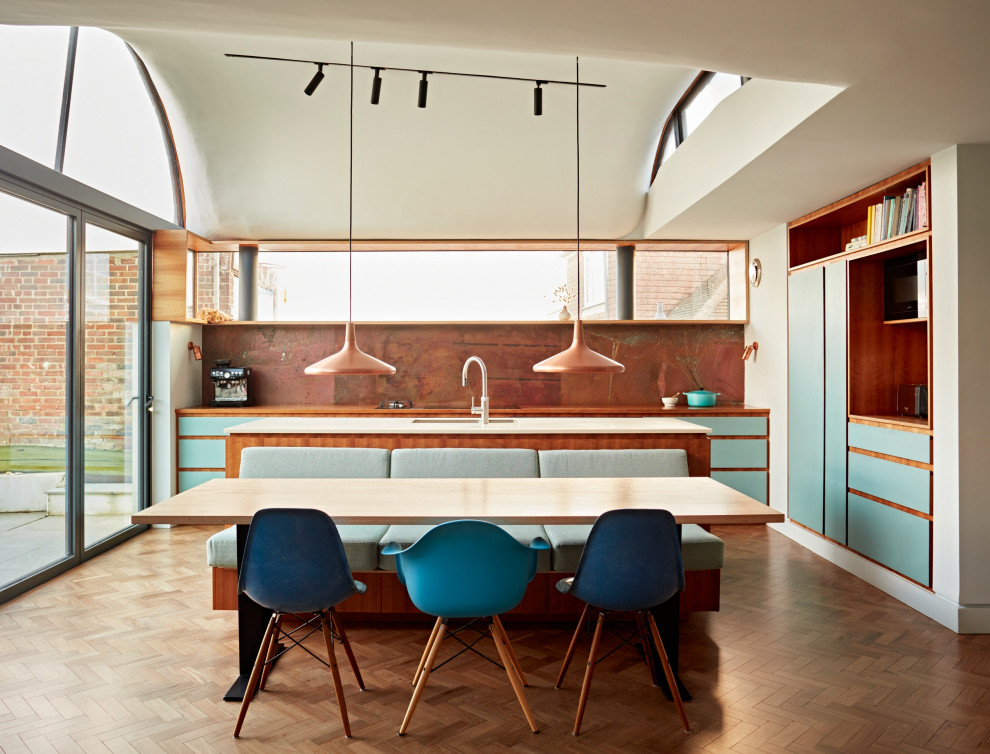Aménagement d'une salle à manger ouverte sur la cuisine rétro en bois de taille moyenne avec un mur bleu, parquet foncé, un sol marron, un plafond voûté et éclairage.