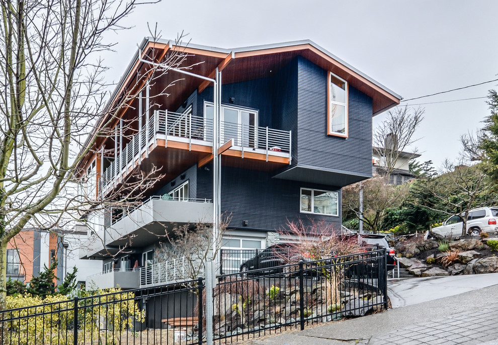 This is an example of a large modern split-level blue house exterior in Seattle with metal siding and a gable roof.