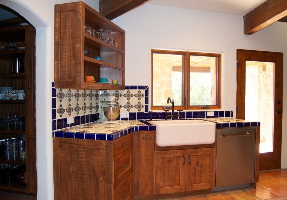 Inspiration for a mid-sized mediterranean kitchen in Phoenix with a farmhouse sink, shaker cabinets, medium wood cabinets, tile benchtops, multi-coloured splashback, cement tile splashback, stainless steel appliances, terra-cotta floors, no island and brown floor.