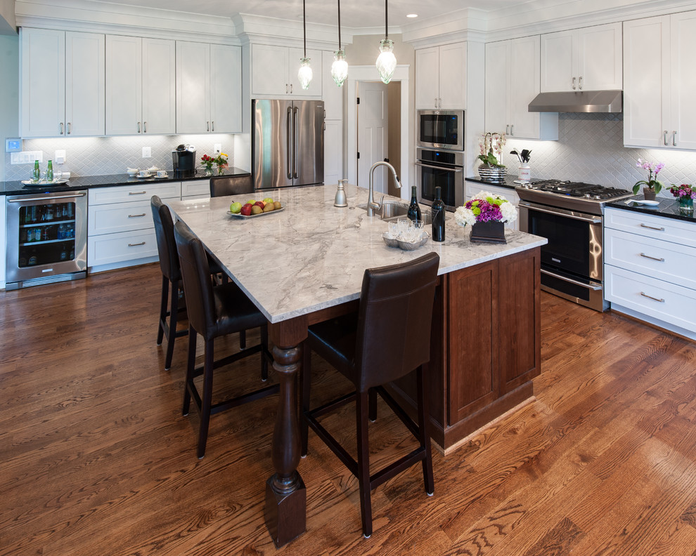 Inspiration for a large traditional l-shaped open plan kitchen in DC Metro with a drop-in sink, beaded inset cabinets, white cabinets, marble benchtops, beige splashback, porcelain splashback, stainless steel appliances, medium hardwood floors and with island.