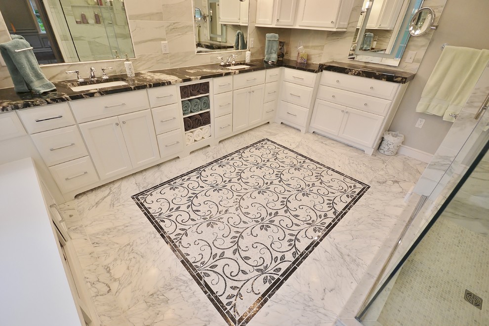 Design ideas for an expansive transitional master bathroom in Philadelphia with recessed-panel cabinets, white cabinets, a double shower, a one-piece toilet, white tile, marble, grey walls, vinyl floors, an undermount sink, marble benchtops, white floor, a sliding shower screen and black benchtops.