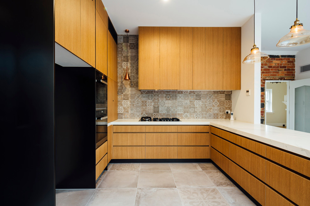 Design ideas for a small contemporary u-shaped eat-in kitchen in Sydney with an undermount sink, flat-panel cabinets, medium wood cabinets, marble benchtops, multi-coloured splashback, stone tile splashback, black appliances, slate floors and a peninsula.