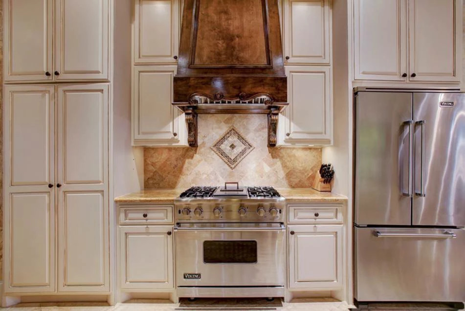 Photo of a mid-sized traditional u-shaped separate kitchen in Houston with beaded inset cabinets, beige cabinets, limestone benchtops, beige splashback, travertine splashback, stainless steel appliances, travertine floors, no island, beige floor and brown benchtop.