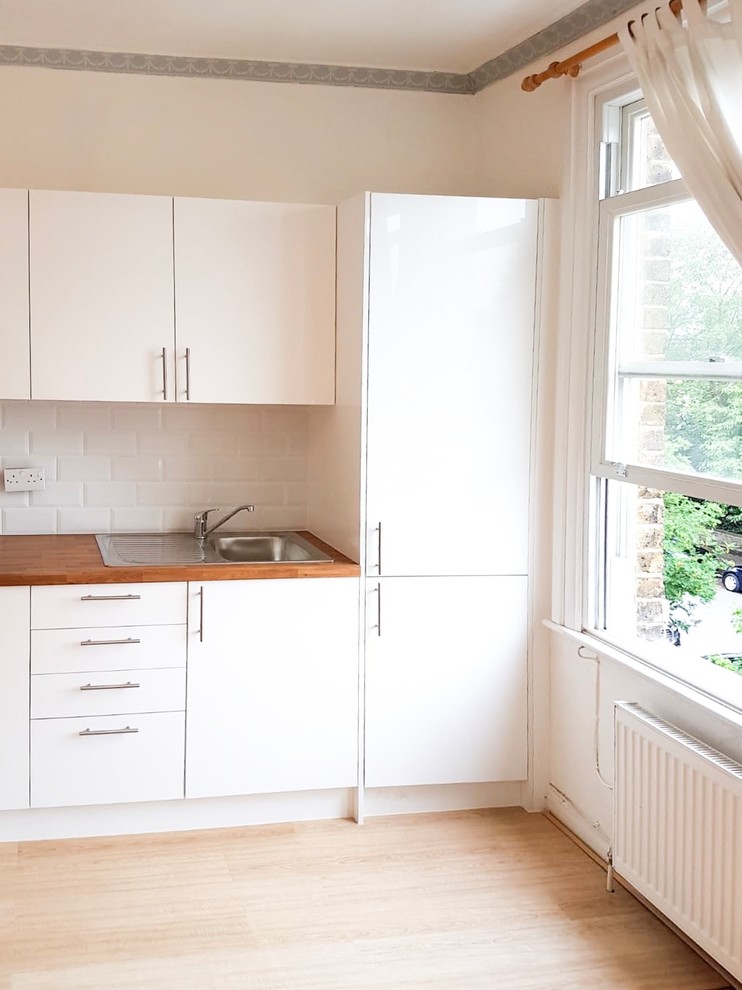 Inspiration for a small scandinavian l-shaped eat-in kitchen in Surrey with glass-front cabinets, white cabinets, wood benchtops, stainless steel appliances, linoleum floors, no island and beige benchtop.