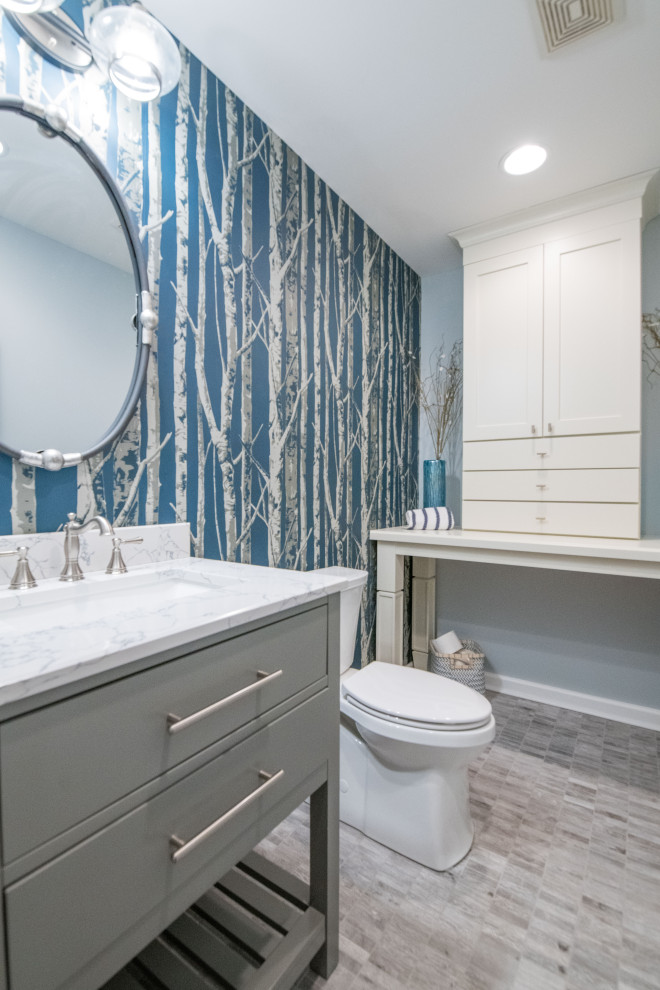 Photo of a mid-sized transitional 3/4 bathroom in Charlotte with flat-panel cabinets, grey cabinets, a two-piece toilet, blue walls, an undermount sink, grey floor and white benchtops.