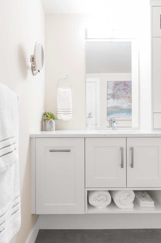 Design ideas for a mid-sized transitional master bathroom in Vancouver with shaker cabinets, white cabinets, a freestanding tub, a corner shower, a one-piece toilet, white tile, ceramic tile, beige walls, ceramic floors, an undermount sink and engineered quartz benchtops.