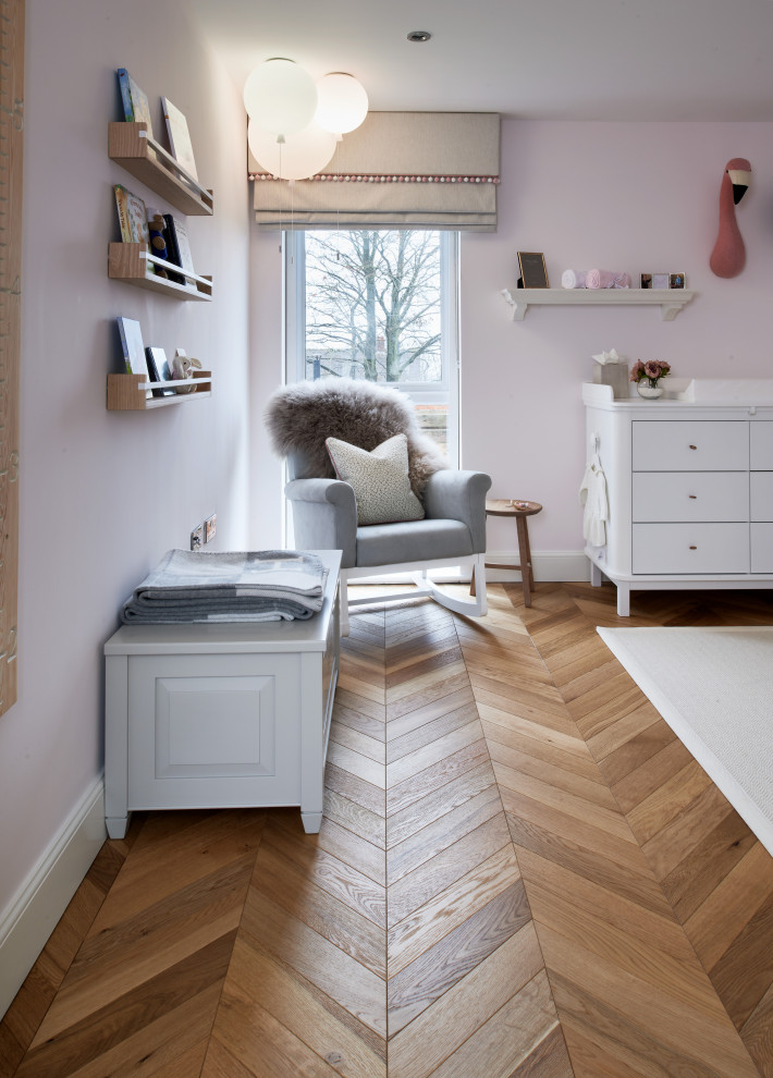 Design ideas for a mid-sized contemporary nursery for girls in Other with pink walls, medium hardwood floors and wallpaper.