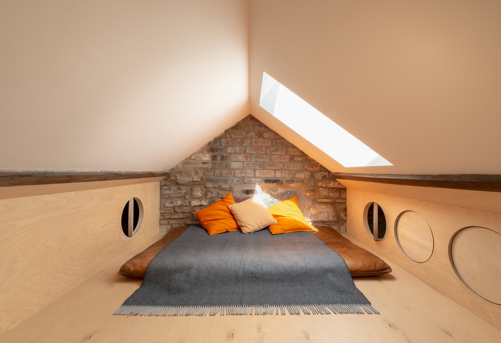 Design ideas for a small scandinavian guest bedroom in London with white walls, light hardwood floors, no fireplace, brown floor, vaulted and panelled walls.